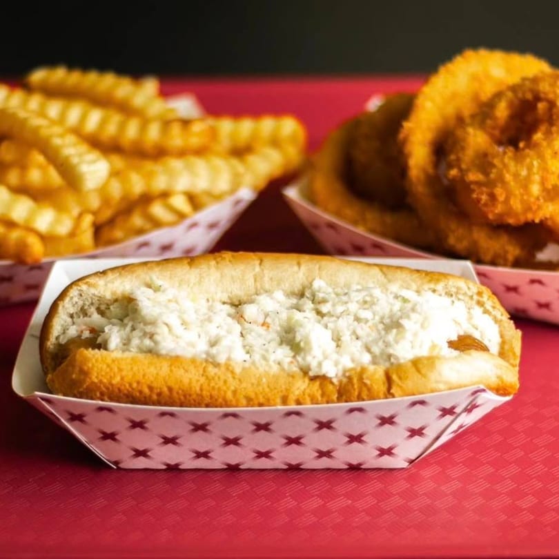 A Griffith's Drive-In hot dog with coleslaw, crinkle-cut fries, and onion rings on a red tray.